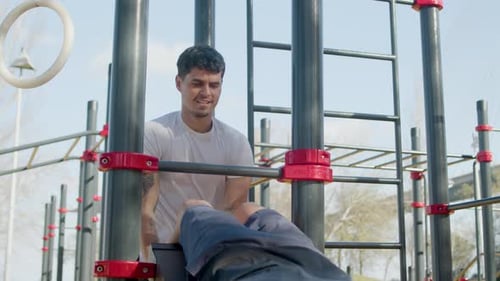 Man Doing Sit Ups with Partner at Outdoor Gym