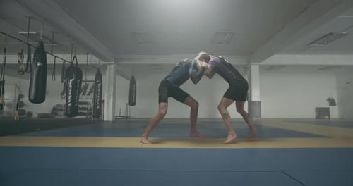 Two Men Practicing Grappling in Gym Setting