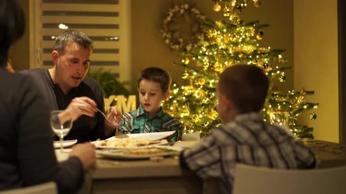 Family Christmas Dinner at Home by Glowing Tree