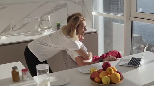 Side View of Bearded Man Working on Laptop Computer Sitting at Home on a Kitchen with Panoramic