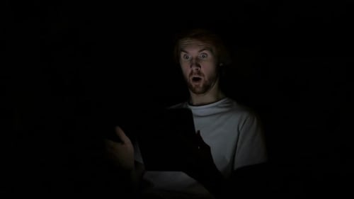 Surprised Man Looking at Tablet in the Dark
