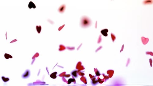 Des confettis en forme de cœur rose qui tombent sur le sol