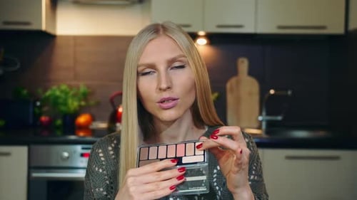 Joven vlogger hablando sobre la sombra de ojos de maquillaje.