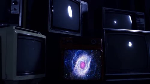 Several Vintage Televisions Stacked in a Dark Room