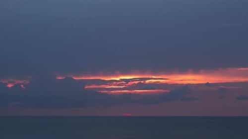 Evening Sky Sunset with Moving Clouds and Solar Disk Sets Into the Horizon Above the Sea