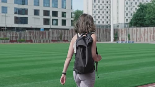 Athlete Woman Goes at Stadium for Fitness Training. Green Grass at Background.