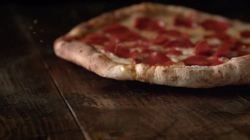 Pepperoni Pizza Being Placed on Dark Table