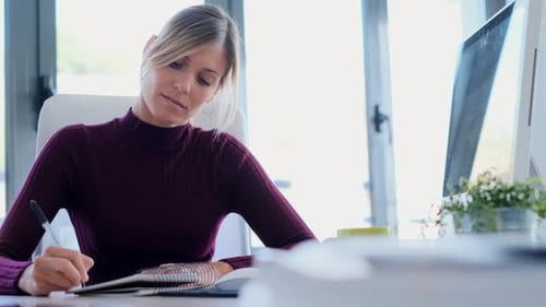 Businesswoman writing in notebook in office