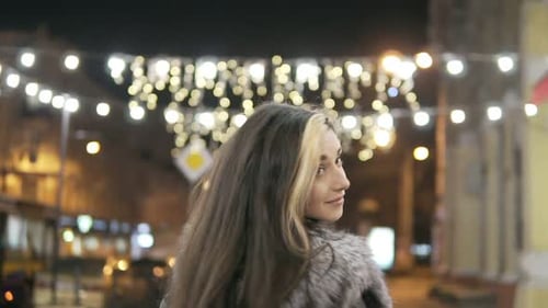 Young Beautiful Pretty Woman Walking and Smiling at City Street in the Night Against Evening Lights