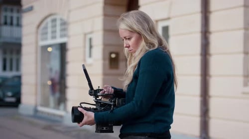 Woman Operates Video Camera on City Street