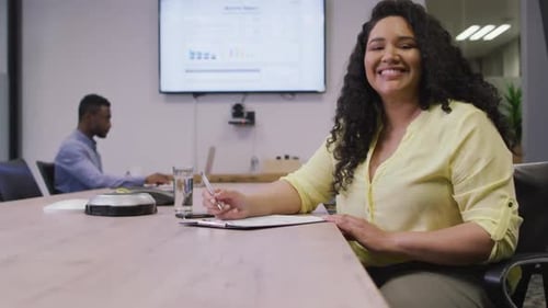 Portrait of smiling biracial businesswoman looking at camera in modern office