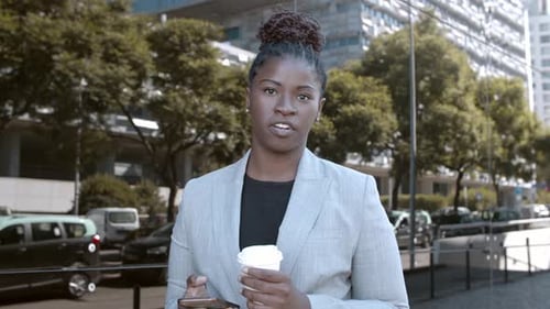 Woman Talking, Holding Coffee and Phone in City