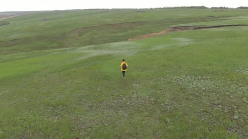 Person Walking Across Green Hills and Landscape