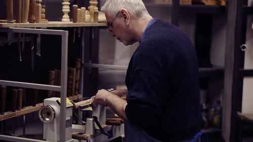 Man Works Wood on Lathe in Workshop