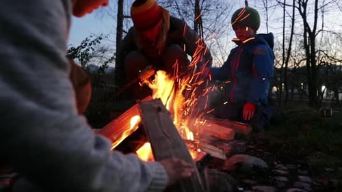 Family at bonfire, boy with firewood