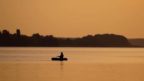 Fischer auf dem Boot gegen Sonnenuntergang. Fischer mit einer Angelrute bei Sonnenuntergang