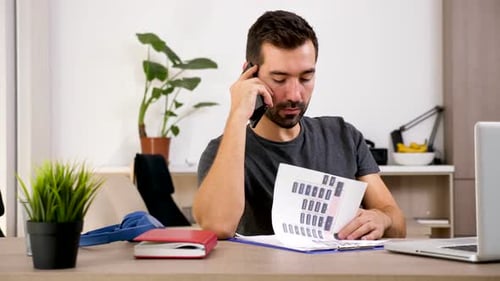 Man Talking on Phone While Reviewing Charts