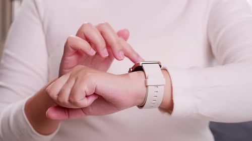 Close up shot of a woman hand who touch and scrolling on a smartwatch in order to quickly check appl