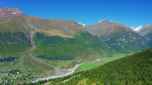 Aerial Drone View of a River in a Mountain Valley Against a Blue Sky
