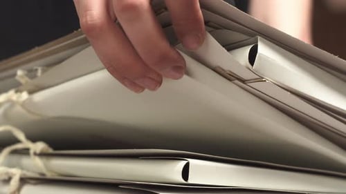 Raising and Sorting Through Folders with Hands Searching for the Right Documents Closeup of Browsing