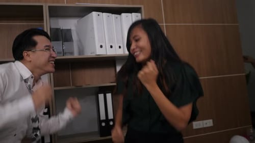 Two joyful colleagues in formal suits dancing cheerful in office