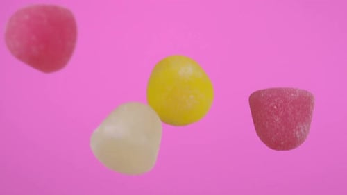 Colorful Candy Pieces Falling on Pink Background