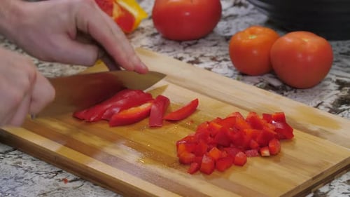 Person Dicing Red Bell Pepper on Wooden Board