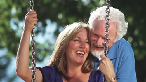 Happy older couple on a park swing.