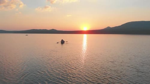 People Sailing on the Boats with Paddles on the River on the Late Sunset