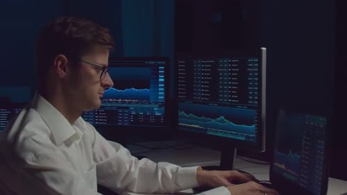 Händler, der nachts im Büro arbeitet und Workstation- und Analysetechnologie verwendet.
