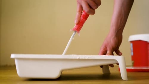 Closeup Shot of a Roller Picking Up Paint From a Plastic Tub
