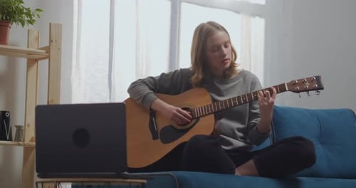 Girl Learning to Play Guitar on Couch at Home