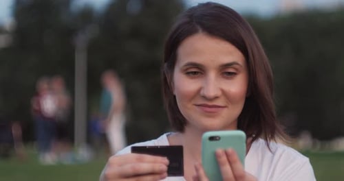 Student on Street with Credit Card and Phone Brunette Woman Sitting on the Bench and Makes Online