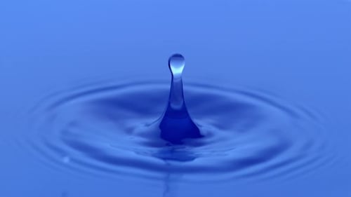 Water Drop Creates Ripples on a Blue Surface