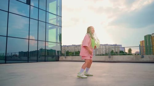 Girl dancing outdoors. Beautiful child with bright green afro hairstyle express emotions in dance