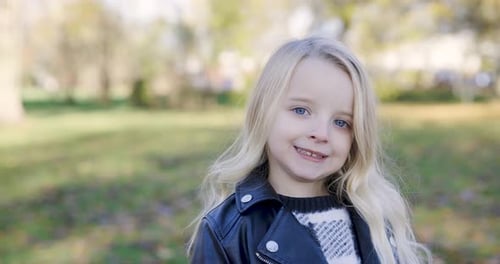 Portrait of blonde girl at park, smiling and looking at camera