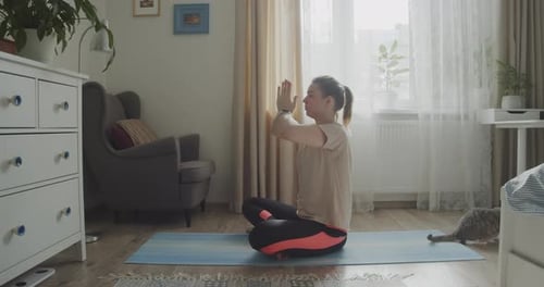 Young Woman Doing Yoga at Home with Cat