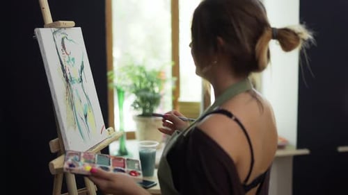 Female Artist in Apron Painting Picture on Canvas in Art Studio