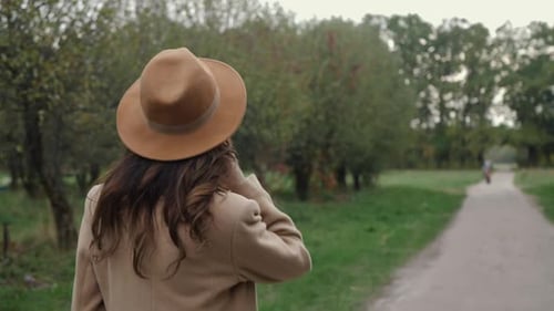 Woman Walking Along Tree Lined Path on Autumn Day