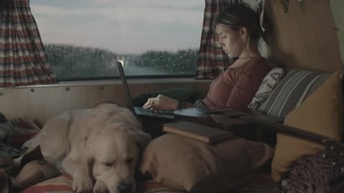 Woman Working in Camper With Dog in Rain