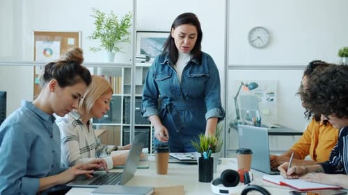 Female Boss Talking To Group of Employees During Business Businessneeting in Office