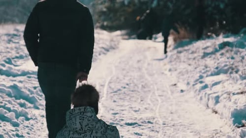 Father Sledding His Daughter in the Snow in a Sunny Winter Forest