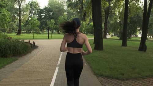Woman Running for Fitness in a Green Park