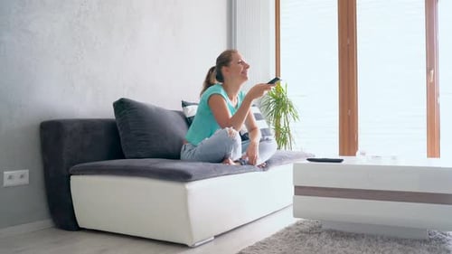 Woman Relaxing with Remote Control on Couch