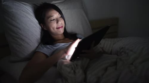 Time lapse of woman using digital tablet on bed at night