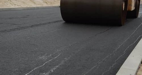 A Large Yellow Steamroller Flatten Hot Asphalt. Builds A New Road