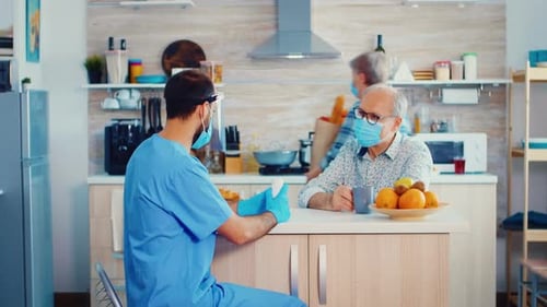 Caregiver Meeting with Senior Adult in Home Kitchen