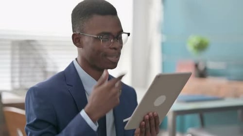 Video Call on Tablet By Young African Businessman in Office