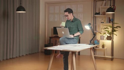 Adult Working on Laptop While Sitting on Desk