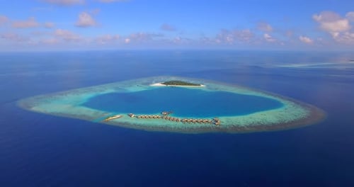 Aerial drone view of scenic tropical island and resort hotel with overwater bungalows in Maldives